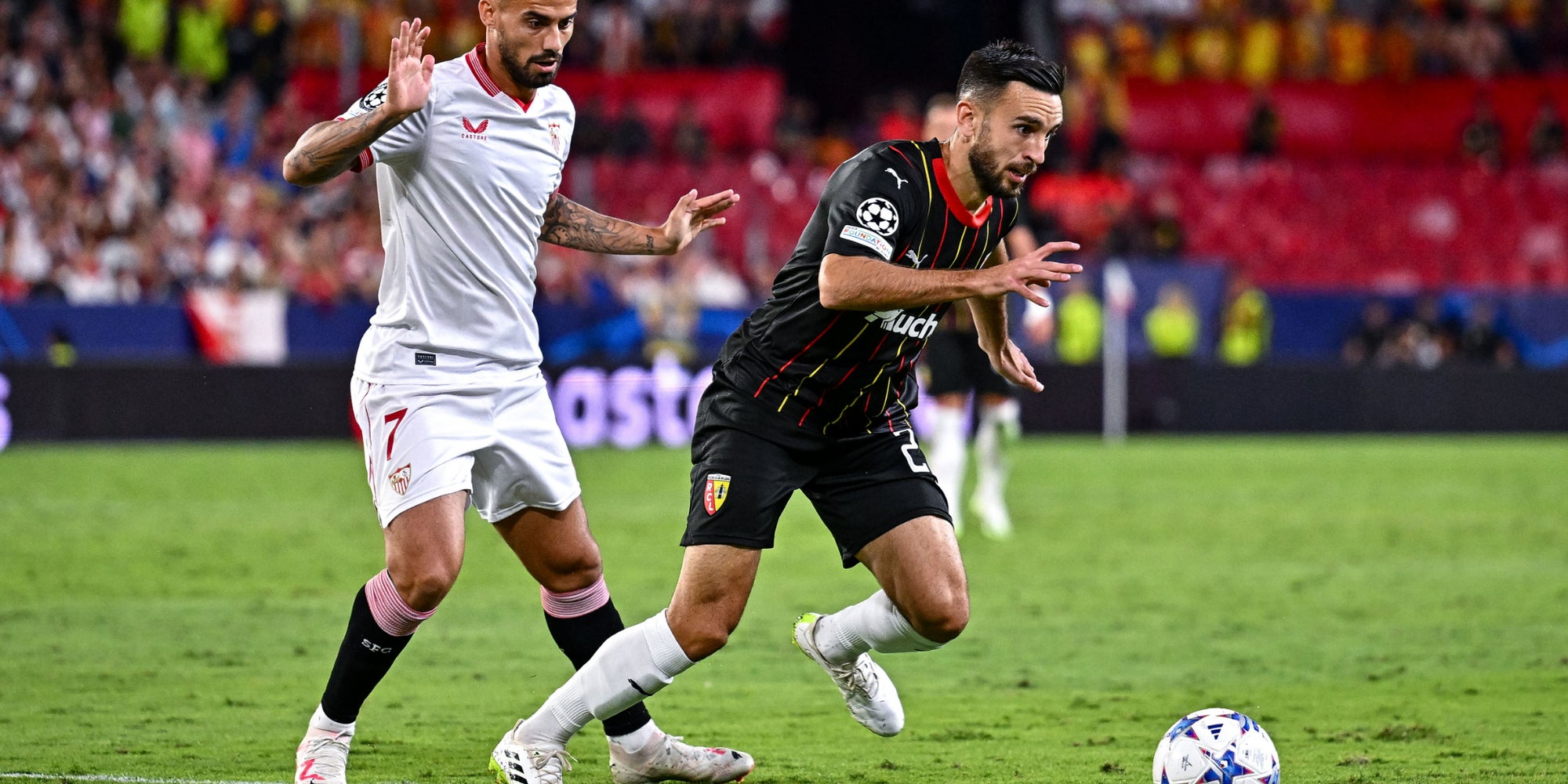 Suso (FC Séville) et Adrien Thomasson (RC Lens) lors du match Séville – Lens, à l’occasion de la 1e journée de phase de groupes de Ligue des Champions, le 20 septembre 2023 au Ramón Sánchez-Pizjuán de Séville.
