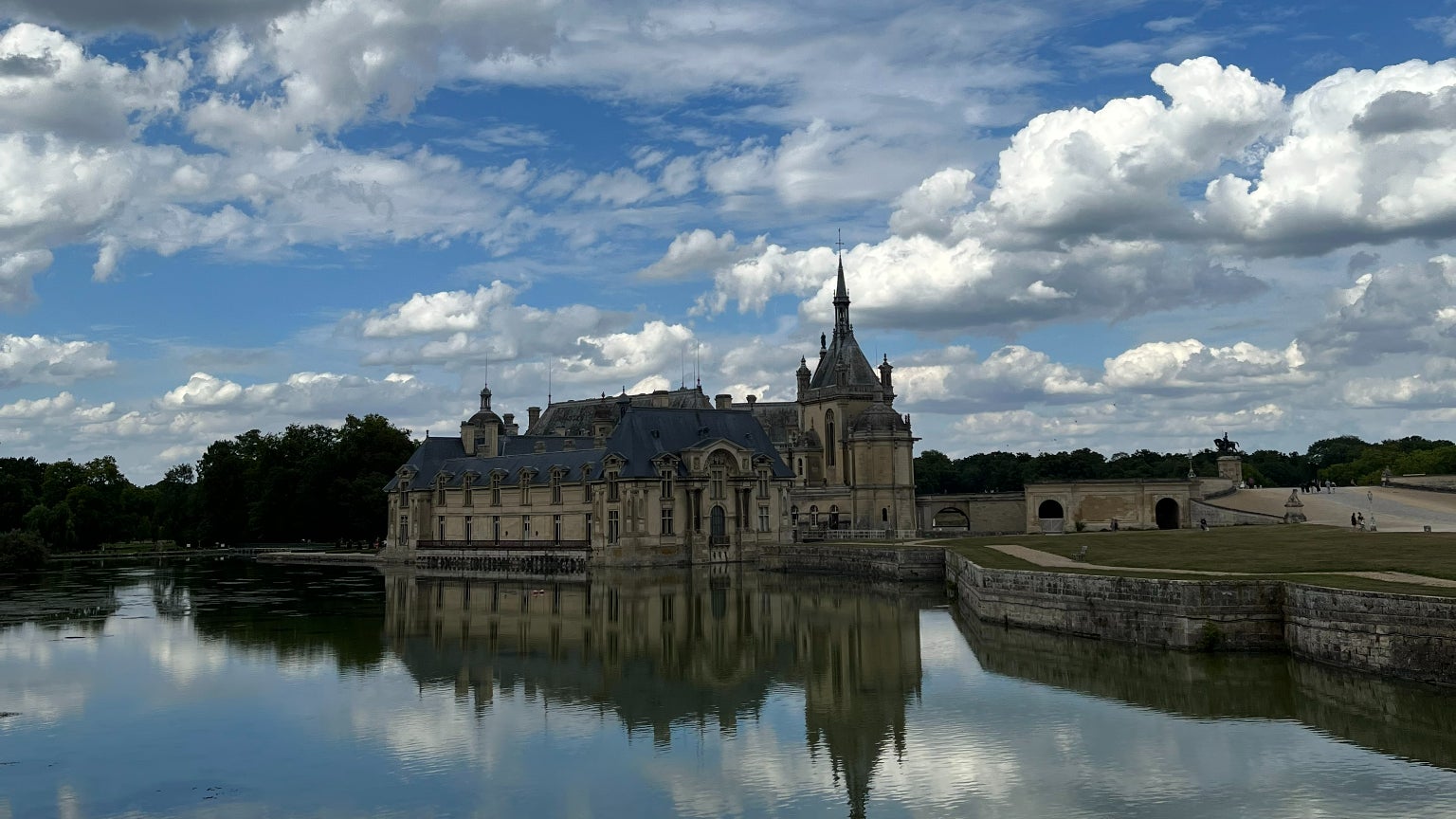 Le château de Chantilly pris en photo avec l'iPhone 13 : les nuages dans le ciel comme les reflets dans l'eau sont parfaitement restitués